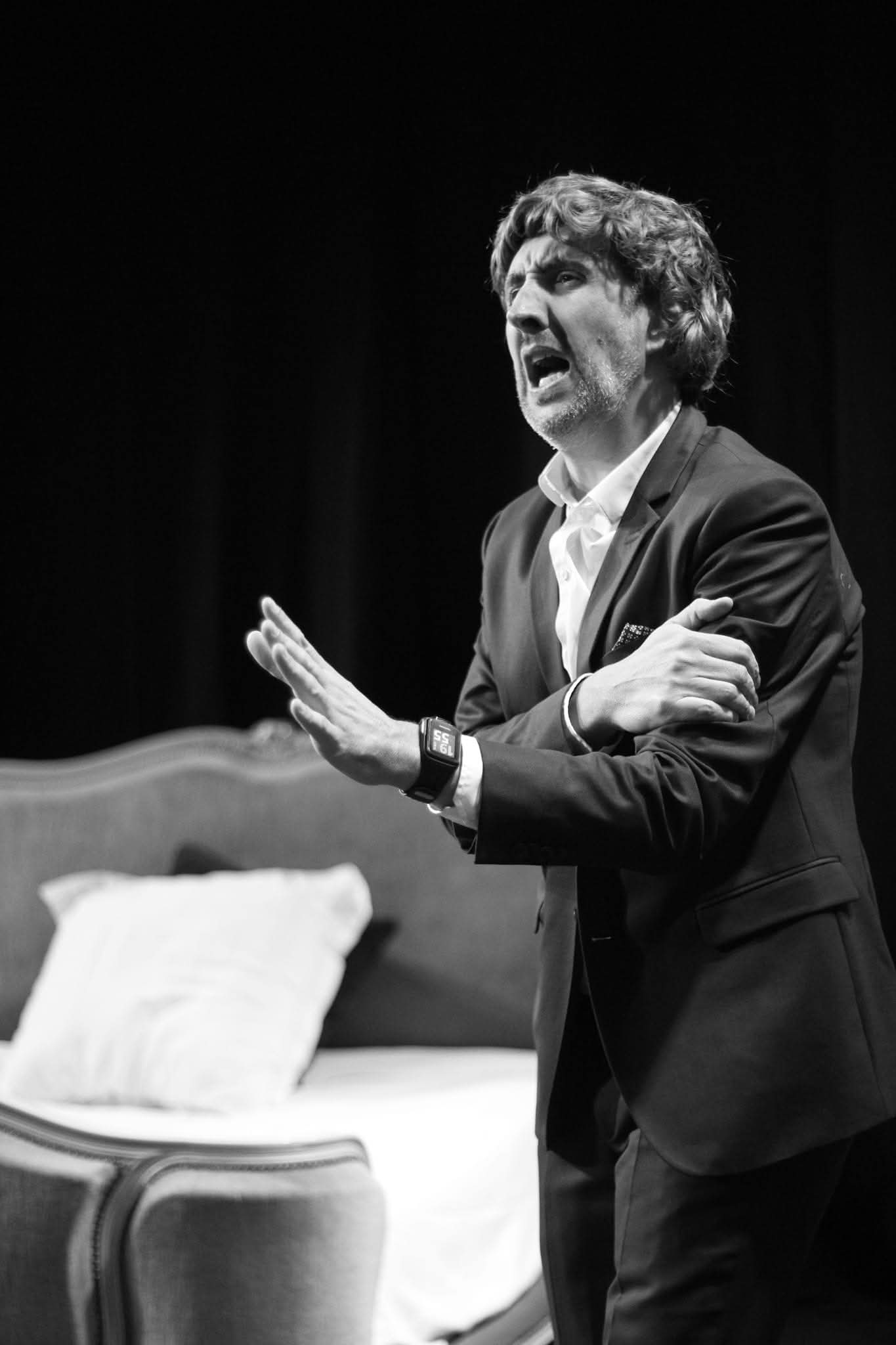 Comedien en costume pres d'un lit de scene dans A vau-l'eau Vaudeville