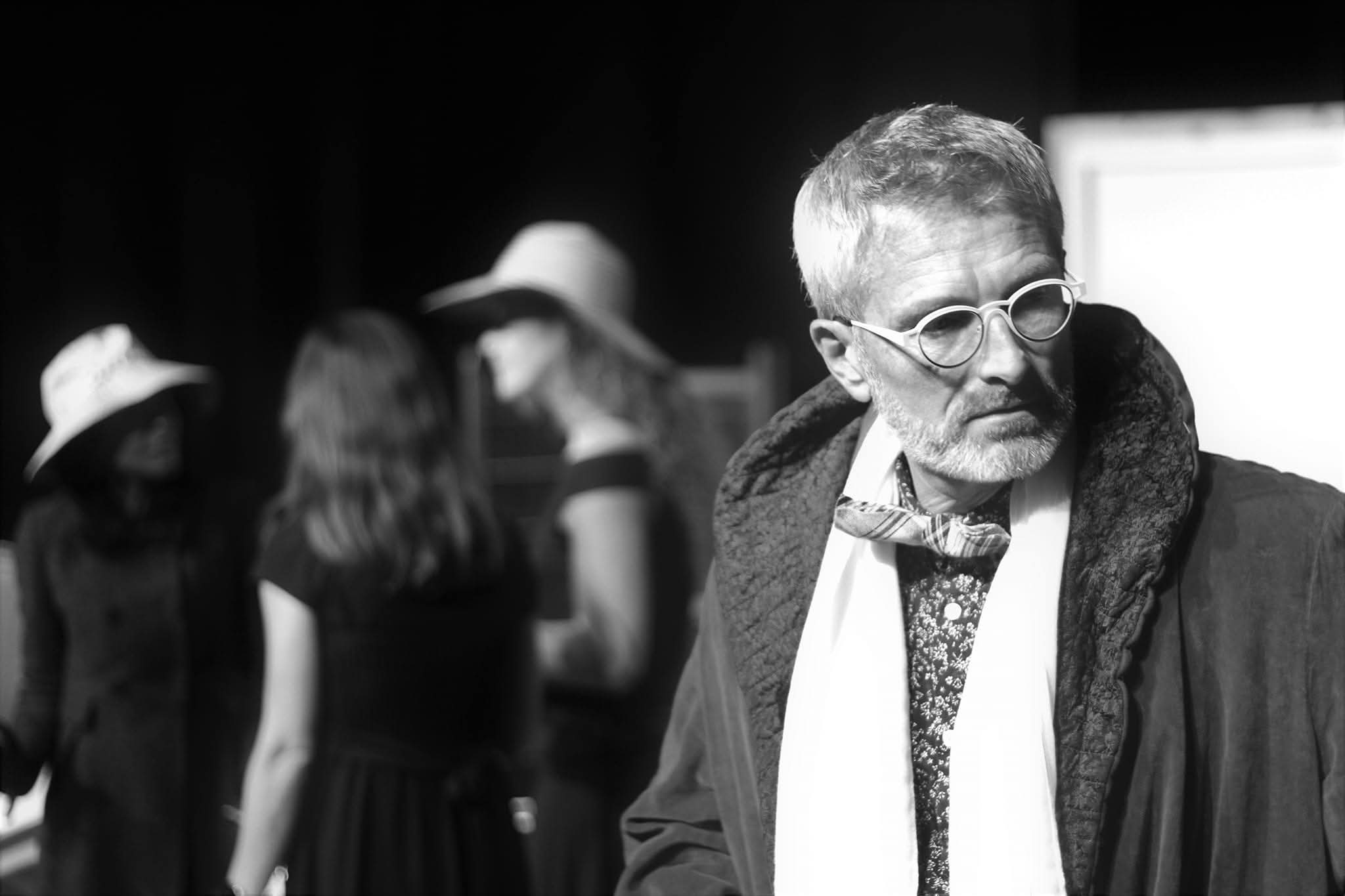 Comedien en premier plan devant le reste de la distribution sur scene